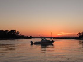 A serene sunset view featuring a boat silhouetted against the colorful sky, perfect for capturing the tranquility of evening on the water.
