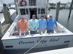 A group of friends poses on the deck of the 'Ocean City Girl' fishing boat, ready for a day of adventure on the water.