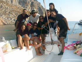 A cheerful group of friends poses on a boat, enjoying their time together against a stunning coastal backdrop — perfect for memorable outings and celebrations on the water.