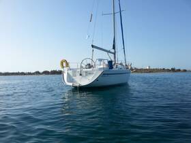 A serene view of a sailboat docked in calm waters, showcasing its elegant design against a clear sky — perfect for sailing enthusiasts and charter opportunities.