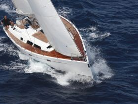 An aerial view of a sleek sailboat cutting through deep blue waters, showcasing its elegant design and sailing capabilities.