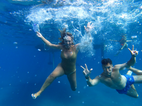 Two friends enjoy a lively underwater moment, showcasing the fun of swimming and exploring the ocean — perfect for adventure seekers and group outings.