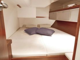 Cozy cabin interior featuring a comfortable double bed with pillows, perfect for relaxing on a boat getaway.
