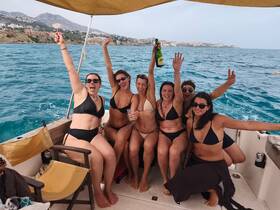 A lively group of friends celebrates aboard a boat, enjoying drinks and the beautiful ocean view — perfect for a fun day on the water.