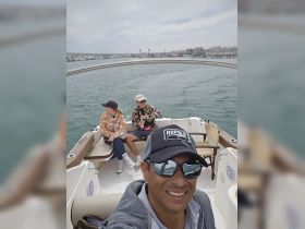 A group enjoys a day on the water, capturing a fun moment aboard a boat with scenic views in the background.
