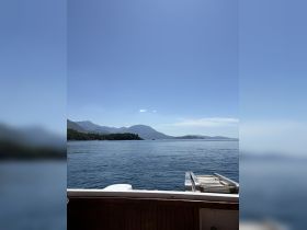 A serene view from the deck of a boat, showcasing calm waters and distant mountains, perfect for a peaceful day on the water.
