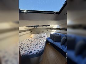 Cozy interior cabin of a boat featuring a comfortable bed and seating area, perfect for relaxing during a day on the water.