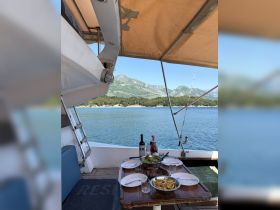 A beautifully set dining table on a boat featuring a delicious spread of grilled meats, fresh salad, and drinks, perfect for enjoying meals while cruising on the water.