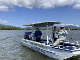 A group of anglers proudly displays their catch aboard a fishing charter, enjoying a day on the water with stunning scenery in the background.