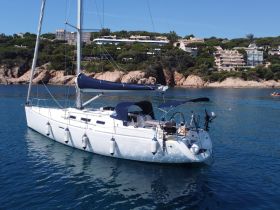 A beautiful sailboat anchored in calm waters, showcasing its sleek design against a scenic coastal backdrop.