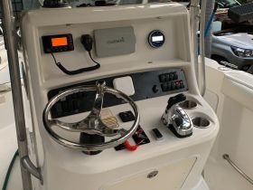 A detailed view of the helm and console area inside a boat, showcasing the steering wheel, controls, and electronic equipment — ideal for navigation and operation.