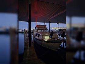 A serene view of a boat docked in a marina at dusk, showcasing its sleek design and illuminated features — perfect for evening outings.
