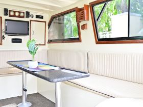 Interior view of a cozy boat cabin featuring comfortable seating and a modern table, perfect for relaxing during your nautical adventures.