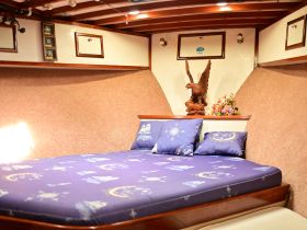 Cozy cabin interior featuring a comfortable bed adorned with nautical-themed pillows, perfect for relaxation during a boating adventure.