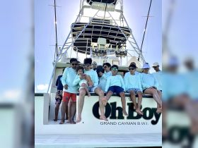 A joyful family gathers on the deck of the 'Oh Boy' boat in Grand Cayman, capturing a memorable moment together under the sun.
