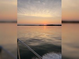 A serene sunset view over calm waters, captured from the deck of a boat, showcasing the tranquil beauty of evening cruises.