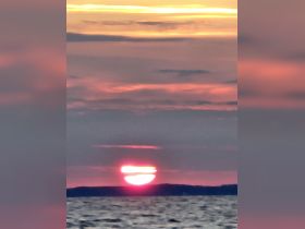 A blurry image of a sunset over the water, creating a serene yet indistinct atmosphere.