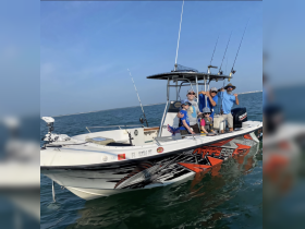 A cheerful family poses on their fishing boat, showcasing a fun day out on the water. Perfect for family fishing adventures and creating lasting memories.