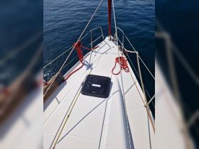 A close-up view of the bow of a sailboat, showcasing its sleek design and the tranquil blue waters surrounding it — perfect for sailing enthusiasts.