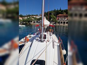 A clear view of a sailboat's deck, showcasing its rigging and design, set against a picturesque coastal backdrop.