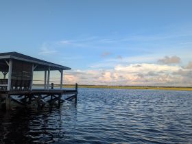 A scenic view of a dock by the water under a clear sky, showcasing the tranquil atmosphere of a waterfront location.