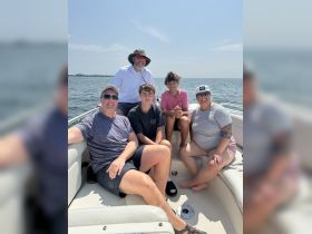 A cheerful family enjoys a day out on the water, capturing memorable moments aboard their boat. Perfect for family outings and summer adventures.