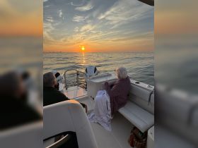 A serene sunset view from a boat, featuring a couple enjoying the peaceful moment together — perfect for romantic getaways or relaxing evenings on the water.