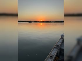A serene sunset view from the side of a boat, reflecting on calm waters — a perfect moment for peaceful evening cruises.