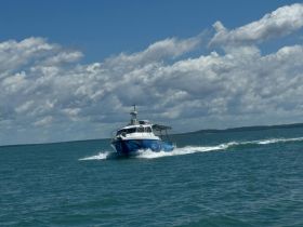 A sleek speedboat navigates through clear waters, showcasing its dynamic design and performance under a bright blue sky.
