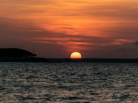 A stunning sunset view over the water, with a boat silhouetted against the vibrant sky — perfect for capturing the beauty of evening cruises.