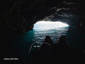 A captivating view from inside a cave as a boat approaches the exit, showcasing the stunning contrast of light on the ocean — perfect for adventure seekers exploring hidden gems.