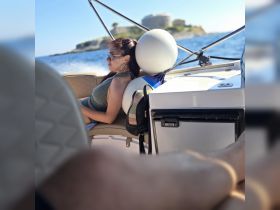 A woman relaxes in the seating area of a boat, enjoying the sun and sea breeze — perfect for a day of leisure on the water.