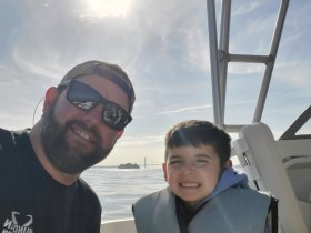A joyful moment captured with a man and a child smiling on a boat, showcasing the fun of family outings on the water.