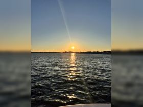 A serene sunset over the water, with beautiful reflections creating a tranquil atmosphere — perfect for evening boat rides.