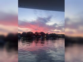 A stunning sunset reflects on the calm waters, creating a picturesque scene perfect for evening boat rides.
