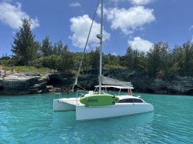 A picturesque scene featuring a catamaran anchored in stunning turquoise waters, with guests enjoying the beautiful island surroundings — perfect for a day of relaxation and exploration.