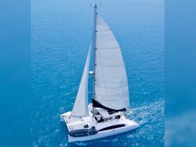 A stunning aerial view of a catamaran sailing through vibrant turquoise waters, showcasing the vessel's sleek design and the beauty of the open sea.