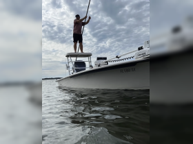 A person paddleboards on a boat, showcasing an active on-water experience amidst a cloudy sky — perfect for adventure seekers.