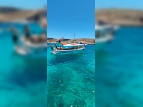 A lively group enjoys a sunny day on a boat in crystal-clear turquoise waters, perfect for swimming and relaxation.
