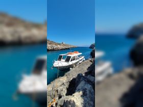 A sleek boat docked along rocky shores, surrounded by crystal-clear waters, perfect for exploring coastal destinations.