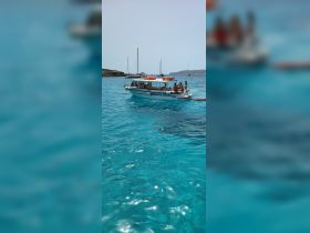 A lively group enjoys a day on the water aboard a boat in stunning turquoise waters, perfect for swimming and relaxation.