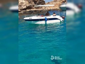 A group enjoys a sunny day on a boat in crystal-clear waters, perfect for swimming and snorkeling adventures.