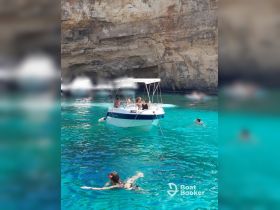 A lively scene of guests enjoying a day on the water, with some swimming and others relaxing on the boat amidst stunning turquoise waters.
