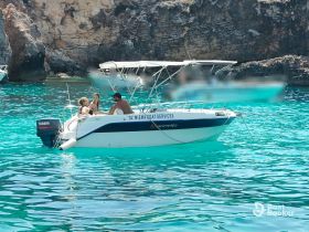 A group enjoys a sunny day on a boat in stunning turquoise waters, perfect for a fun-filled day of swimming and relaxation.
