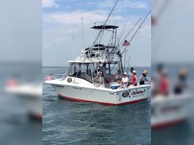 A lively group enjoys a fishing trip aboard the 'Christine P' boat, showcasing camaraderie and adventure on the water.