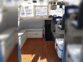 Interior view of a boat cabin featuring seating and storage for life jackets, showcasing a clean and functional design ideal for comfortable outings.