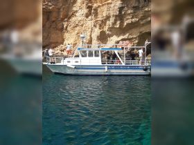A group of people aboard a boat near a rocky coastline, enjoying a day on the water — perfect for exploring scenic destinations.