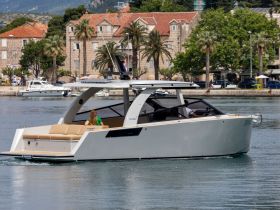 A sleek yacht glides through the water, showcasing its elegant design and spacious seating area, perfect for luxury cruising.
