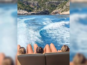 A group of friends relaxes on the back of a boat, enjoying the stunning coastal scenery and the thrill of the ride — perfect for a day of adventure on the water.