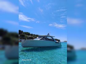 A sleek yacht anchored in crystal-clear waters, showcasing its modern design against a backdrop of lush greenery and a bright blue sky.